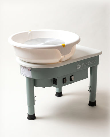 The Kiln Crafts Poppy pottery wheel in sage green with a white splash pan