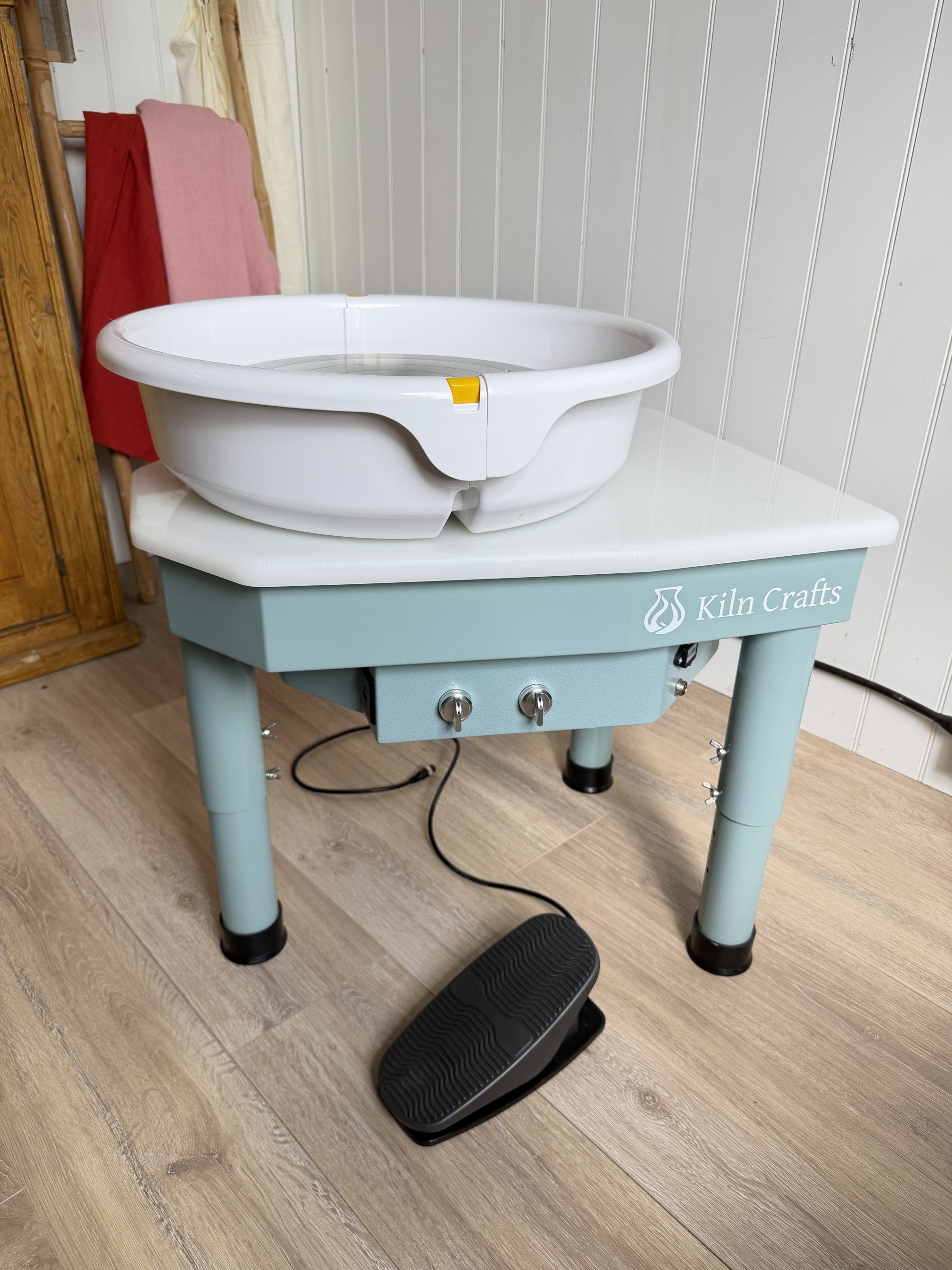 The new Daisy pottery wheel set up at home with its foot pedal on a wooden floor