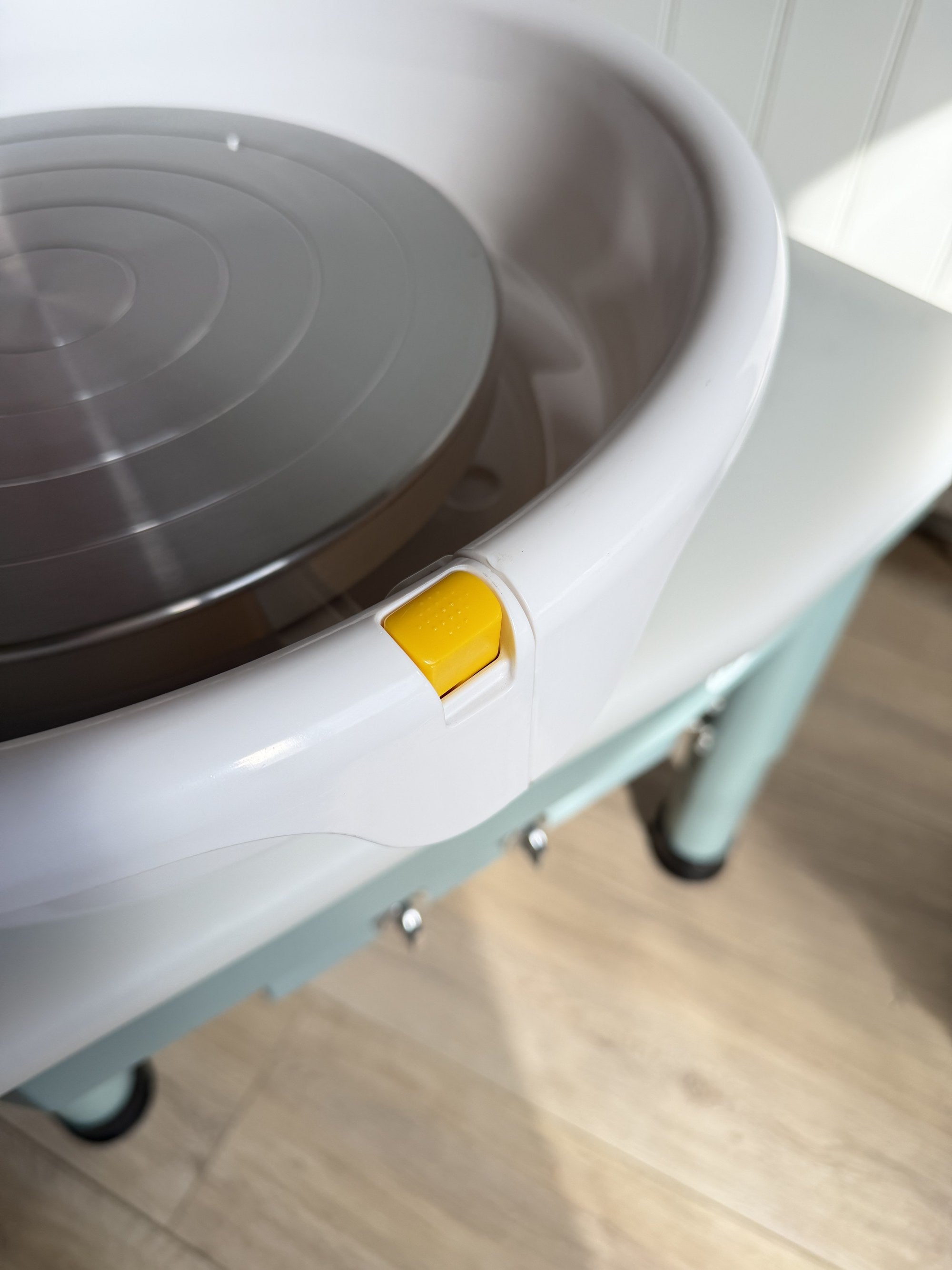 Yellow push-button release on the Daisy pottery wheel splash pan