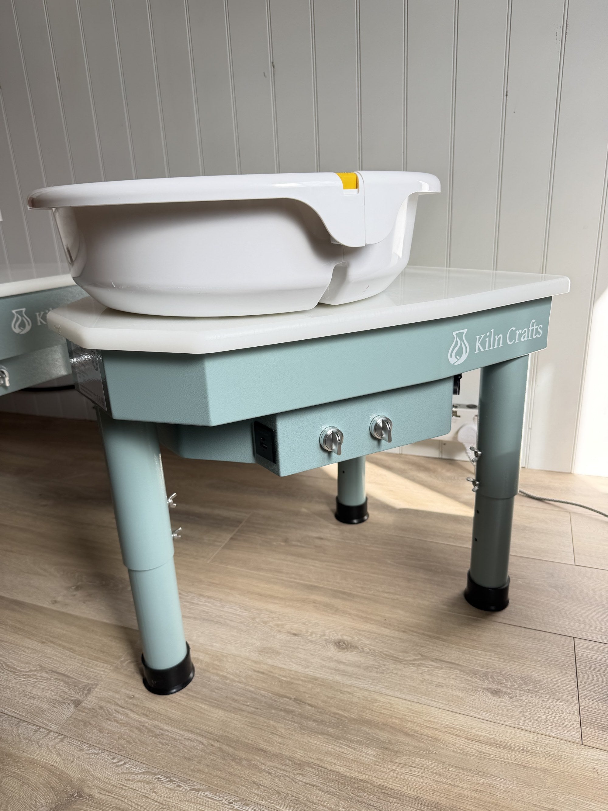 Side view of the Daisy pottery wheel at home showing adjustable legs and USB ports