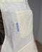 Close-up of the Milk Kiln Crafts Craft Apron chest pocket and woven Kiln Crafts label