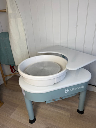 Kiln Crafts Thistle Wheel Shelf fitted to the Thistle direct-drive wheel — white top on a sage bracket, three-quarter view